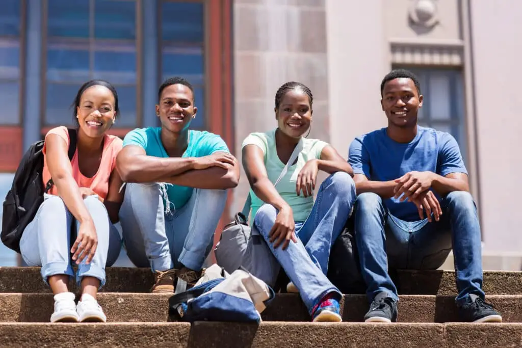 Diverse group of students sitting on university steps smiling