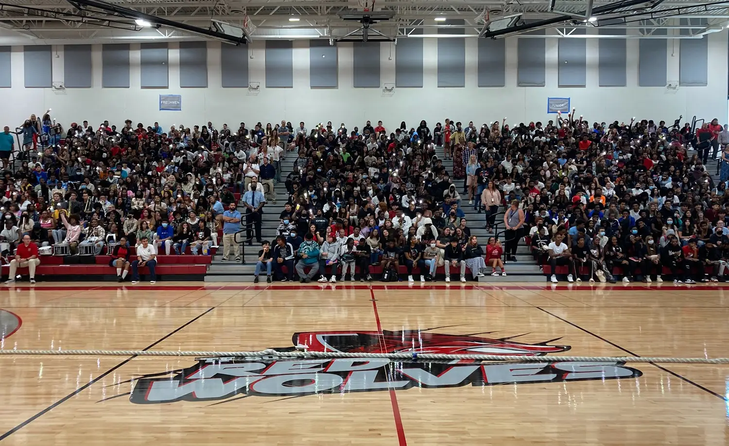Crowded school gymnasium with students sitting on bleachers