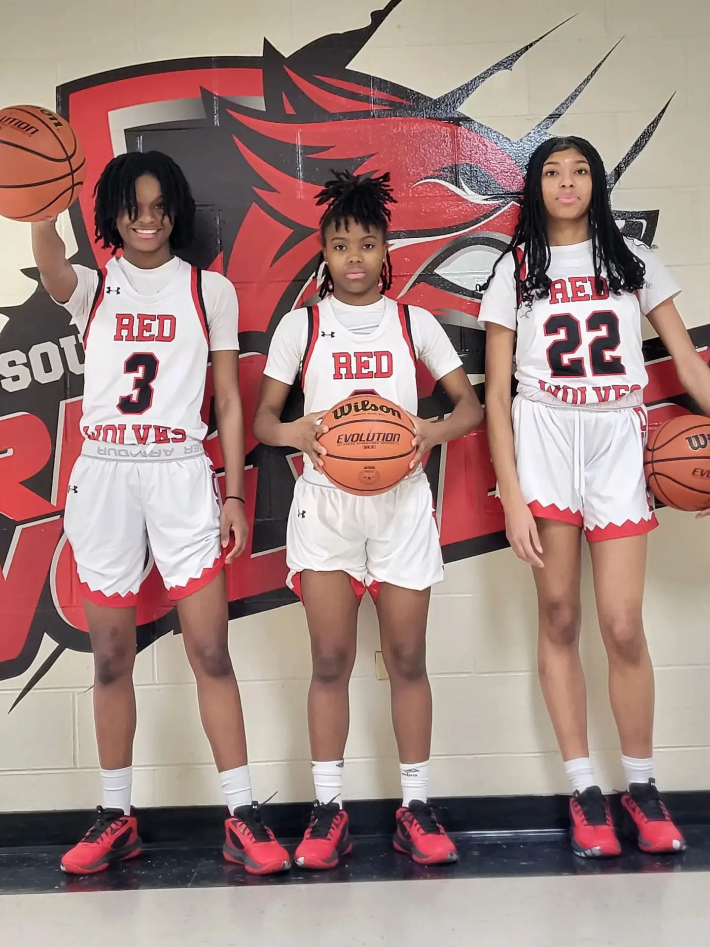 Three high school basketball players in Red Wolves uniforms