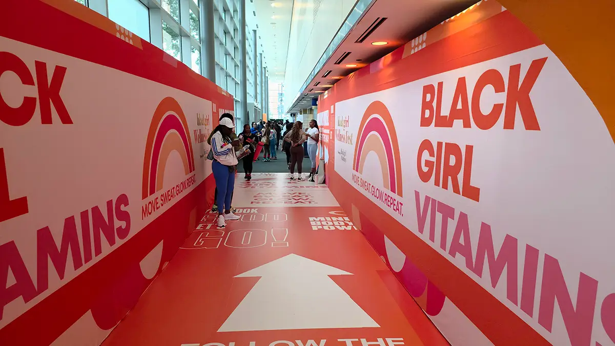 Colorful event corridor with 'Black Girl Vitamins' branding and motivational signs