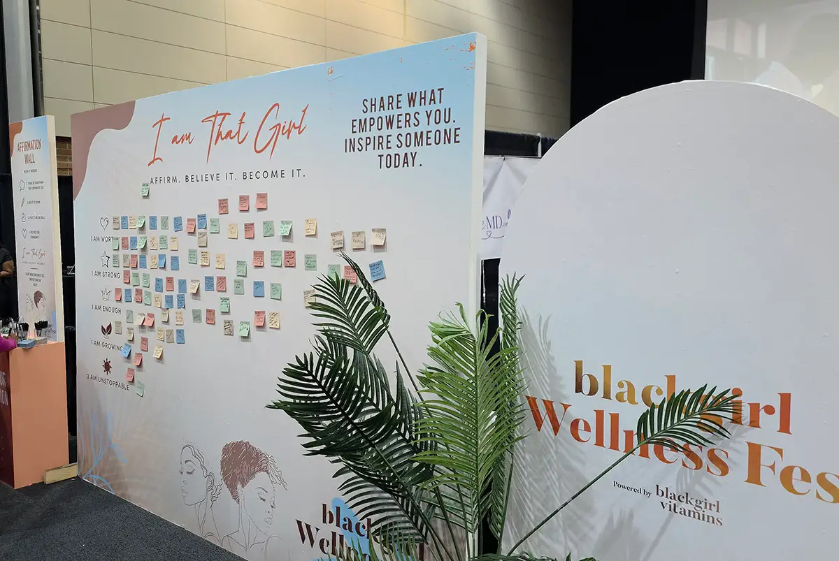 Black Girl Wellness Fest wall with motivational notes and plant decor
