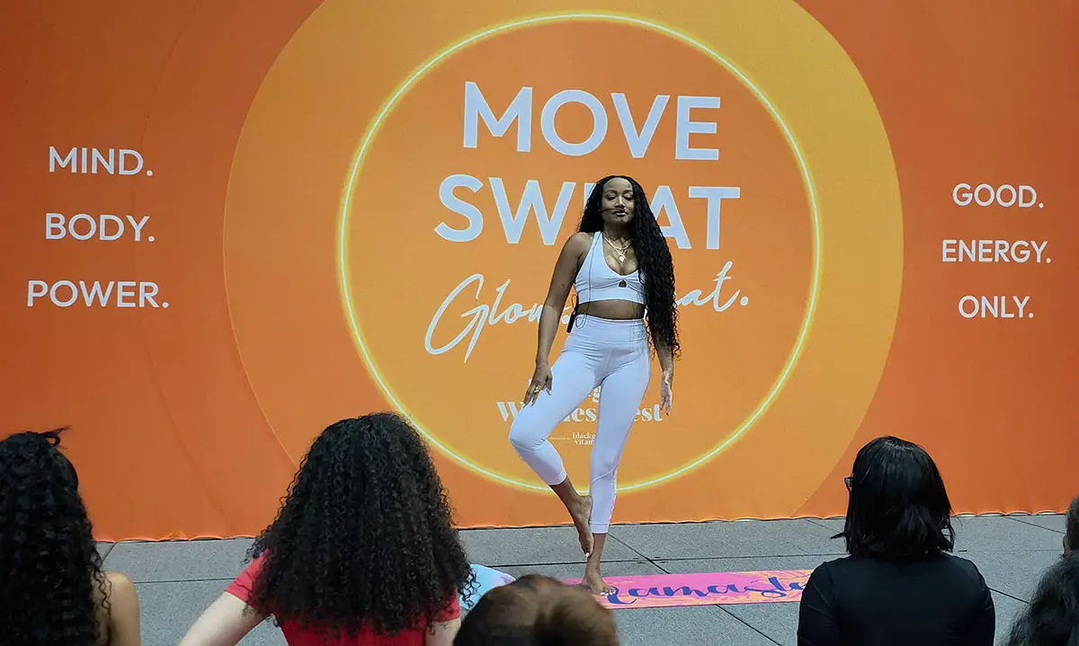 Woman leading wellness workout event with motivational orange backdrop